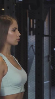 Uzun dalgalı saçlı neşeli genç bir sporcu, boynunu havluyla siler, yoğun bir spor seansından sonra memnuniyet saçar. Spor salonunun hareketli atmosferi, arka planda ağırlıklar, onun kararlılığını ve zindelik yolculuğunu arttırır.