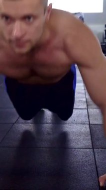 Odaklanmış beyaz bir atlet şık bir spor salonunda etkileyici fiziğini sergileyerek şınav çekiyor. Kamera sorunsuzca süzülüyor, modern bir fitness merkezinde güç ve güç kazanırken gözlerindeki kararlılığı yakalıyor.