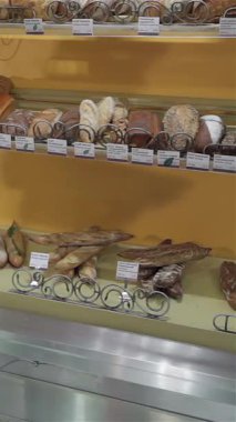 Önlüklü çekici beyaz bir kadın canlı bir pastanenin parıldayan vitrinleri boyunca yürür, dijital tabletle bir dizi lezzetli pişmiş malın envanterini titizlikle çıkarır. Sıcak ortam baştan çıkarıcı bir aromayla doludur.