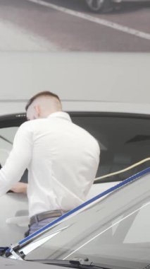 Şık bir işadamı, parlak araçlarla çevrili çağdaş bir bayilikte çarpıcı mavi bir otomobili inceliyor. Bu dinamik sahne araba alışverişinin heyecanını yakalıyor. Lüks ve satın almanın cazibesini gösteriyor.