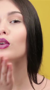 Uzun, düz, esmer, büyüleyici bir Asyalı kadın hava öpücüğü gönderir, çıplak omuzları parlak sarı bir arka plana doğru parlar. Parlak dudakları ve büyüleyici gülüşü neşe ve cazibe saçıyor. Seyircileri neşeli dünyasına davet ediyor.