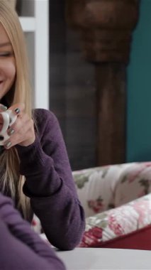 Neşeli, genç, beyaz bir çift şık bir kafede keyifli bir anı paylaşıyor, kahvelerini yudumluyor ve canlı sohbetler ediyorlar. Sarışın güzel kadın erkek arkadaşına ışıldıyor, sıcaklık ve bağlantıyla dolu bir atmosfer yaratıyor.