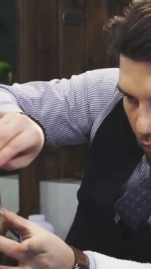 Şık bir berber dükkanında, yetenekli bir berber, genç erkek müşterisini ustura, ustalık ve sanatsallıkla titizlikle tıraş eder. Sıcak, klasik atmosfer deneyimi geliştirir, berberlerin uzmanlığını ve müşterileri ön plana çıkarır.