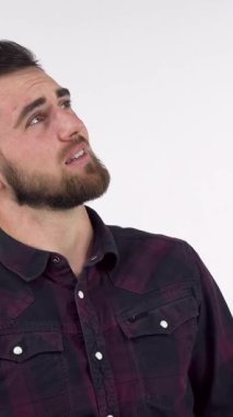 Yakışıklı sakallı bir adam, kulaklarını kapatırken yüzünü buruşturur ve kendini kahpelikten korumaya çalışır. Bu çarpıcı görüntü, kargaşanın ortasında huzuru bulma mücadelesini gösteren endişe ve stresin özünü yakalıyor.