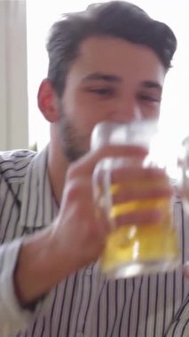 Üç neşeli arkadaş, açık renk ve koyu saçlı iki adam, neşeyle soğuk bira bardaklarını canlı bir barda tokuşturuyorlar, mutluluk ve dostluk saçıyorlar. Bu canlı sahne, arkadaşlığın ve kutlamaların özünü yansıtıyor.