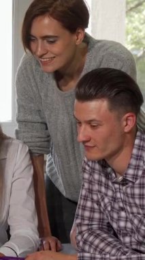 Dört üniversiteli arkadaş, iki kadın ve iki erkek bir dizüstü bilgisayarın etrafında toplanmış projeleri için beyin fırtınası yapıyorlar. Parlak gülümsemeleri ve nişanlı ifadeleri takım çalışmasının ve akademik heyecanın heyecanını yansıtıyor.