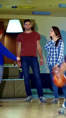 Bir grup arkadaş neşeli bir beşlik çakar ve sarışın bir adam güvenli bir şekilde kırmızı bowling topunu aşağı yuvarlar ve zaferin heyecanını yakalar. Bowling salonundaki bu enerjik sahne genç yetişkinler arasında kahkaha ve dostluk yayıyor.