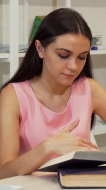 Genç bir kız öğrencinin büyüleyici bir portresi, çenesi elinde dinleniyor, gülümserken sıcaklık saçıyor parlak, düzenli bir çalışma alanında kitap çalışırken. Bu neşeli genç, öğrenmenin sevincini temsil ediyor. İlham verici şeylerle çevrili.