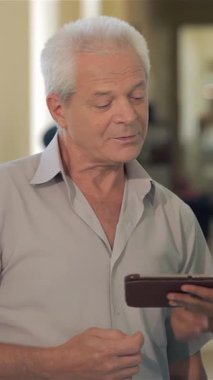 Canlı yeşil üniformalı şefkatli bir beyaz doktor gri saçlı son sınıf öğrencisiyle sıcacık bir dijital tablet üzerinde hayati bilgiler sunuyor. Bu samimi an, modern sağlık hizmetlerinin özünü yansıtıyor.