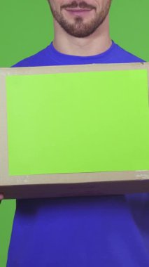 Parlak mavi gömlekli neşeli, sakallı bir teslimatçı bir karton kutuyu sunarken geniş bir gülümseme sergiliyor ve içindekileri merak uyandırıyor. Bu canlı sahne profesyonelliği ve sıcaklığı yansıtıyor, çarpıcı yeşil bir arka plana karşı kurulmuş,