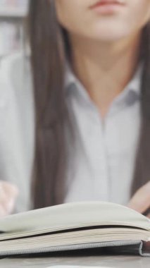 Kararlı bir kız öğrenci, sıcak, davetkar bir kütüphanede yüksek edebiyat raflarıyla çevrili kitabına dalmış durumda. Not defteri açık ve yanında parlak bir dizüstü bilgisayarla akademik hırsını ve odaklanmasını yayıyor.