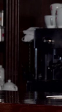 Neşeli bir barmen, şık bir ekose gömlek ve bakımlı bir sakal ile ışıldayan ahşap tezgahta köpüklü bir bardak bira sunar. Sıcak ışıklandırma ve kırsal dekorla zenginleşen barın davetkar atmosferi sahneyi hazırlar.