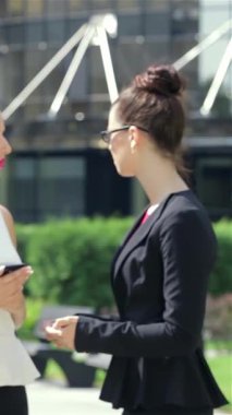 Hareketli bir şehir manzarasında, şık genç bir iş kadını tabletiyle kendinden emin bir şekilde etkileşime geçiyor, profesyonellik ve cazibe yayıyor. Canlı bir yeşillik zeminine kurulmuş kısa gülüşü ve sohbetteki meslektaşları davetkar bir davet yaratıyor.