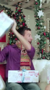 Heyecanlı genç bir çift, şık kış kıyafetleri içinde, sıcacık bir Noel diyarında birbirlerine güzel hediyeler veriyorlar. Oda parıldayan ışıklarla parıldıyor. Renkli süslerle süslenmiş muhteşem bir Noel ağacı.