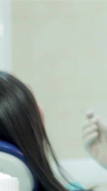 Maske ve eldiven takmış kendini işine adamış genç bir dişçi, parlak ve klinik bir ortamda hastaların dişlerini titizlikle inceliyor. Işıldayan diş aletleri ve odaklı ışıklandırma profesyonellik atmosferi yaratarak,