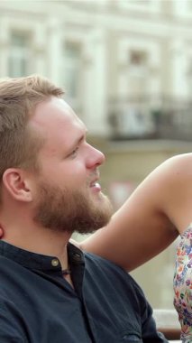 Genç ve hoş bir çift, güneşli bir parkta, bir kızın şefkatle erkeklerin kucağına tünediği neşeli bir anı paylaşırken neşe saçıyor. Işıldayan gülümsemeleri ve şefkatli bakışları gençlik romantizminin özünü özetliyor.