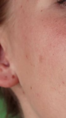 Çarpıcı bir yakın plan çekimi canlı kızıl saçları ve büyüleyici yeşil gözleri olan neşeli bir kadını yakalıyor. Işıl ışıl gülüşü yeşil renkli bir arka planda sahneyi aydınlatıyor. Kusursuz cildi ve büyüleyici ifadesi güven ve mutluluk saçıyor.