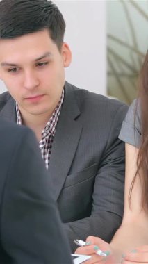 Keskin profesyonel giysiler içinde odaklanmış genç bir çift şık, modern bir ofiste bir analistle canlı bir iş görüşmesine aktif olarak katılıyor. Kararlı ifadeleri ve ilgili vücut dilleri güçlü bir sinerjiyi yansıtır.