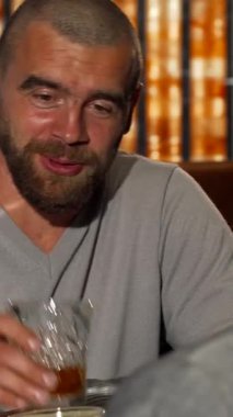 Bakımlı sakallı karizmatik bir adam, şık barın ışıltısında parlayan viski bardaklarıyla bir arkadaşıyla neşeli bir konuşma yapar. Zarif dekorlarla süslenmiş davetkar ortam, yoldaşlığı kutlamak için mükemmel bir zemin hazırlıyor.