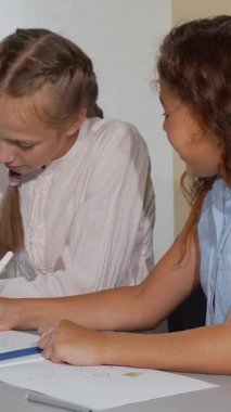 İki okul arkadaşı, neşeli kızıl saçlı bir kız ve onun sarışın arkadaşı, sanat dersleri sırasında canlı çizimler getirirken hareketli bir şekilde sohbet ediyorlar. Bu canlı sahne çocukluk yaratıcılığının ve dostluğunun özünü güzel bir şekilde yansıtıyor.