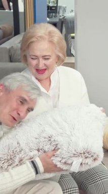 Zevkli bir son sınıf çifti şık bir mobilya mağazasında lüks yastıklar seçiyor, sıcaklık ve sevgi saçıyorlar. Neşeli yaşlı kadın, yumuşak beyaz saçları ve parlak rujuyla, kocasıyla bir kahkaha paylaşıyor,