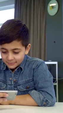 Koyu renk saçlı, şık bir kot gömlek giymiş keyifli bir genç çocuk, babasının akıllı telefonundaki resimlere hevesle göz atıyor, dijital bir maceraya atlıyor. Yakışıklı Afrikalı Amerikalı baba, bu samimi anı oğluyla paylaşıyor.