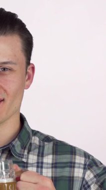 Neşeli genç bir adam neşeli bir sırıtışla köpüklü bir bardak bira kaldırır, kutlama ve arkadaşlığın özünü yakalar. Şık ekose gömleği bu anı canlı toplantılar ve hafta sonu şenlikleri için ideal kılıyor.