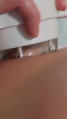 Yetenekli bir kadın masör zarif bir şekilde zarif bir masaj makinesiyle kadının beline doğru manevra yapar, derin rahatlama ve gençleşme sağlar. Bu samimi yakın çekim, dinginliğin içindeki izleyiciyi saran tendeki nazik baskıyı vurgular.