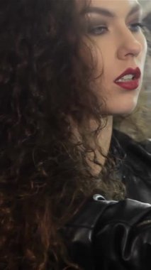 Çarpıcı bir bayan bisikletçi, canlı bir atölyede kendine güven ve tarz yayarak motosiklet koltuğuna yaslanıyor. Onun tatlı kıvırcık saçları özgürce süzülür başını şakayla eğerek, macera ve özgürlük ruhunu somutlaştırır.