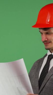 Turuncu bir şapka takan neşeli genç bir mimar titizlikle detaylı planlarını incelerken gururla ışıldıyor. Canlı yeşil bir krom anahtar zemin, kendine güveni ve bulaşıcı gülümsemesi coşkuyla parlıyor.