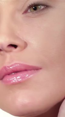 Kusursuz makyajlı çarpıcı beyaz bir kadının büyüleyici yakın çekimi yumuşak, parlak beyaz bir arka plana hafifçe yanağını okşuyor. Parlak cildi ve büyüleyici yeşil gözleri saflık ve zarafet saçıyor, hayranlık uyandırıyor ve ilham veriyor.