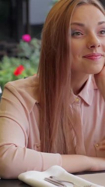 İki güzel kadın, neşe saçan, büyüleyici bir kafe terasında oturup, keyifli kokteyllerin tadını çıkarırken birbirlerinin hikayelerini anlatıyorlar. Bereketli yeşillik ve çiçek açan yer şekillendirici bir zemin oluşturarak neşeli atmosferlerini güçlendirir.