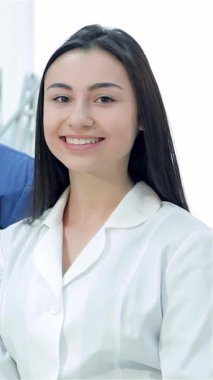 Zarif ve modern bir diş hekiminde, neşeli bir kadın stajyer ve kendine güvenen bir erkek dişçi bir aradalar, sıcaklık ve profesyonellik yayıyorlar. Baş parmakları ve parlak gülümsemeleri olağanüstü bir hasta bakımına olan bağlılıklarını yansıtıyor.