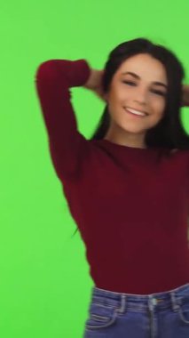 Uzun, dalgalı saçları olan enerjik genç bir kadın hayat dolu yeşil bir zemine ışıldarken buklelerini şaklatarak çeviriyor. Onun kaygısız duruşu ve ışıl ışıl gülüşü gençlik güzelliğinin ve coşkunluğunun özünü somutlaştıran kendine güven ve canlılık saçıyor.