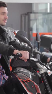 Tarz sahibi beyaz bir adam parlak siyah bir motosiklete güvenerek oturur ve odaklanmış bir ifadeyle gidonu ustalıkla sola doğru hareket ettirir. Parıldayan benzin deposuna dokunduğunda heyecanı yayılıyor. Kendini seçmenin heyecanıyla boğuyor.