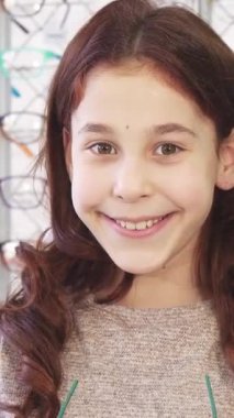 Kıvırcık saçlı ışıl ışıl küçük bir kız, canlı bir gözlük mağazasında son moda güneş gözlüğü mankenliği yaparken mutluluk saçıyor. Bu canlı sahne çocukluk sevincinin heyecanını ve mükemmel gölgeleri seçmenin heyecanını özetliyor.