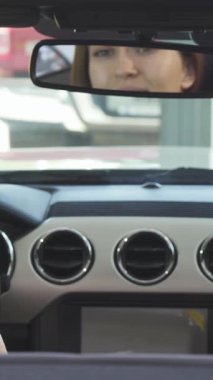 Uzun, dalgalı saçları olan neşeli genç bir kadın, üstü açık arabasında otururken omzunda ışıl ışıl bir gülümseme, etrafa güven ve neşe saçıyor. Bu canlı sahne özgürlüğün ve maceranın coşkulu duygusunu özetliyor.