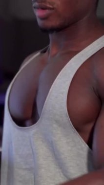 Etkileyici fiziğini sergileyen Afrikalı bir adam enerji dolu enerjik bir spor salonundaki halterlere ağırlık plakaları ekliyor. Bu güçlü sahne onun sarsılmaz kararlılığını yansıtan güç eğitiminin ruhunu somutlaştırıyor.