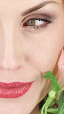 Çekici bir yakın plan, dalgalı sarı saçlı güzel bir kadın, parlak gülüşü sahneyi aydınlatırken yüzünü canlı yeşil yapraklarla nazikçe okşuyor. Bu büyüleyici portre, ilkbaharın özünü temsil ediyor, zarifliğini gösteriyor.