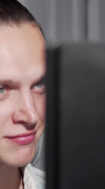 Çarpıcı mavi gözleri olan odaklanmış genç bir adam dinamik bir video çağrısına dalmış, bakışları dikkatle parlayan bilgisayar ekranına sabitlenmiş. Modern çalışma alanının gösterişli tasarımı, şık dekor ile süslenmiş, canlı atmosferi arttırır