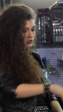 Çekici beyaz bir kadın motorcu, parlak bir helikoptere güvenle uzanır, kıvırcık saçlarını neşeli bir yetenekle arkaya atar. Şık bir siyah deri ceket ve kot şort giymişti. Cesaret ve macera saçıyordu. Mükemmel bir şekilde yakalıyordu.