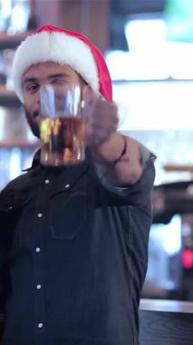 Neşeli bir grup arkadaş, Noel Baba şapkalarıyla süslenmiş, barın önünde kadehlerini neşeyle kaldırıyorlar, sıcaklık ve dostluk saçıyorlar. Barmenlerin neşeli tebessümleri sayesinde hayat dolu atmosfer gelişiyor.