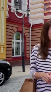 Saf neşe saçan iki neşeli kız, keyifli bir şehir caddesinde geziniyorlar, her biri şık alışveriş çantalarına sarılmış, keyifli bulgularla dolu. Bulaşıcı gülüşleri ve ışıl ışıl gülüşleri renkli binaların resimsel zeminini aydınlatıyor.