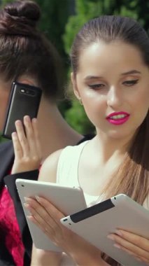 Canlı bir şehir zemininde, üç güçlü iş kadını dinamik iletişime daldırılıyor, biri telefonla, diğeri ise parlak bir tablet üzerinde işbirliği yapıyor. Şık kıyafetleri ve azimli ifadeleri canlı bir atmosfer yayıyor.