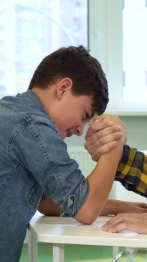 Neşeli bir baba ve genç oğlu, parlak ve modern bir masada, pencereden içeri güneş ışığı akan canlı bir bileklik güreşi yapıyorlar. Çekici Afrikalı Amerikalı baba gururla ışıldıyor. Kararlı oğlu tüm gücünü sergiliyor.