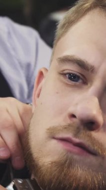 Bu çarpıcı yakın plan yakışıklı bir genç adamın sakalını ustalıkla kesen kendini adamış bir berberi gözler önüne seriyor, sanatın ve bakımının hassasiyetini vurguluyor. Berber dükkanları şık bir ortam yaratıyor. Müşteri ve berber arasındaki yakın ilişkiyi geliştiriyor.