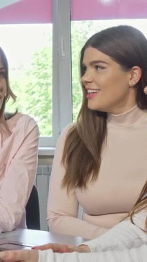 Canlı üç üniversite öğrencisi güneşli bir sınıfta sohbet ediyor ve gülüyorlar, yüzleri neşe ve arkadaşlıkla parlıyor. Sıcak atmosfer işbirliği ruhuyla dolu. Fikirlerin beyin fırtınası yapıyorlar.