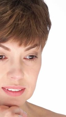 Zarif, orta yaşlı, beyaz tenli bir kadın nazikçe çenesine dokunuyor, kendine güven ve dinginlik saçıyor. Yumuşak ifadesi ve davetkar bakışları, güzellik ve cilt temaları için ideal sıcak bir atmosfer yaratıyor.