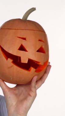 Canlı kırmızı dudakları olan neşeli genç bir kadın tuhaf bir şekilde oyulmuş Cadılar Bayramı balkabağıyla selfie çekerek neşeli bir enerji yayar. Neşeli sahne onun heyecanını ve tatilin büyüleyici ruhunu yakalıyor. Seyircileri eğlenceye davet ediyor.