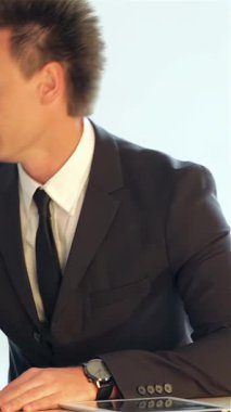 Özel dikim takım elbise giymiş iki genç erkek işadamı, şık bir dizüstü bilgisayarda sergilenen ve odaklanma ve kararlılığı yansıtan bir iş planını canlı bir şekilde tartışıyor. Parlak, çağdaş ofis ayarları